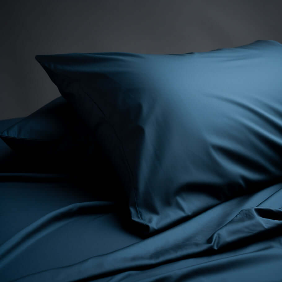 A set of Premium Cotton Sateen Housewife Pillowcases in Navy Blue on a dark background.